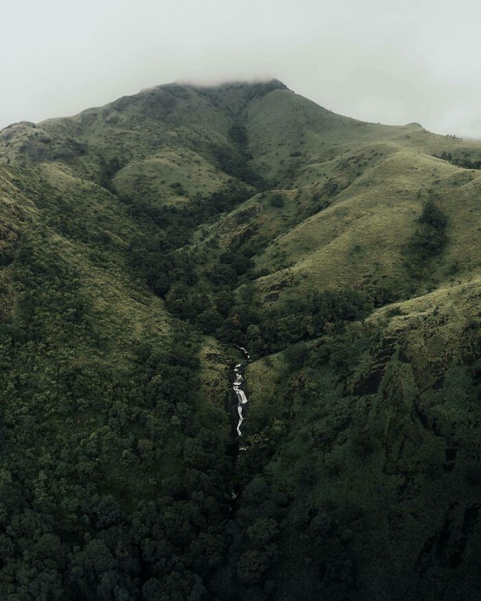 Aerial photo by photographer showing a lush green mountain landscape with a waterfall.