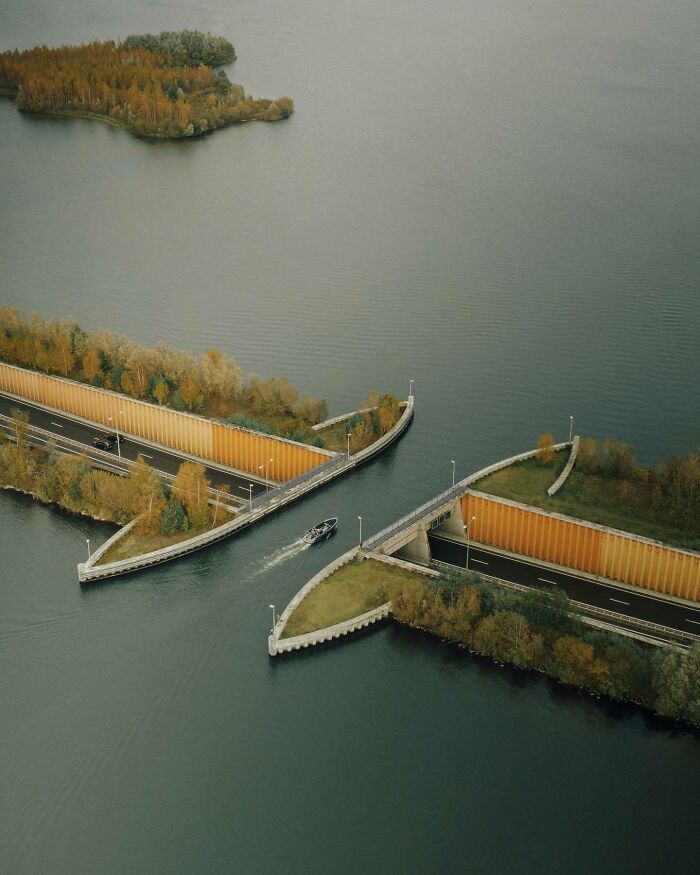 Aerial view of a boat navigating through a unique waterway over a road, showcasing the world from a different angle.