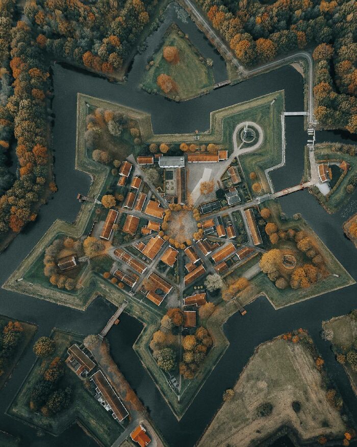 Aerial photo of a star-shaped fort surrounded by water, showcasing unique architectural design from above.