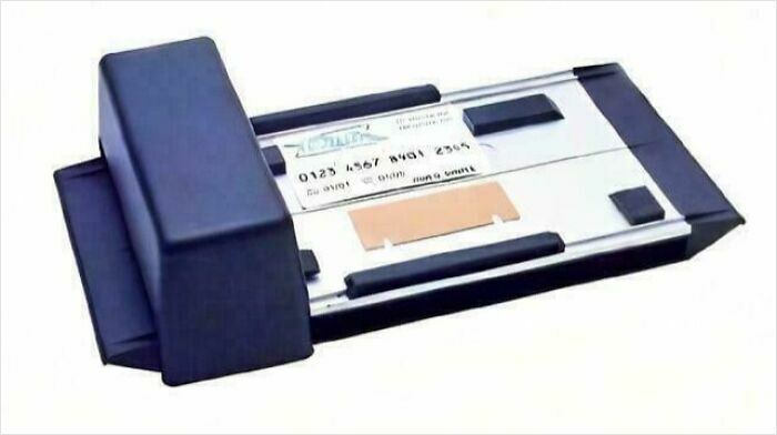 Old credit card imprinter machine on a white background.