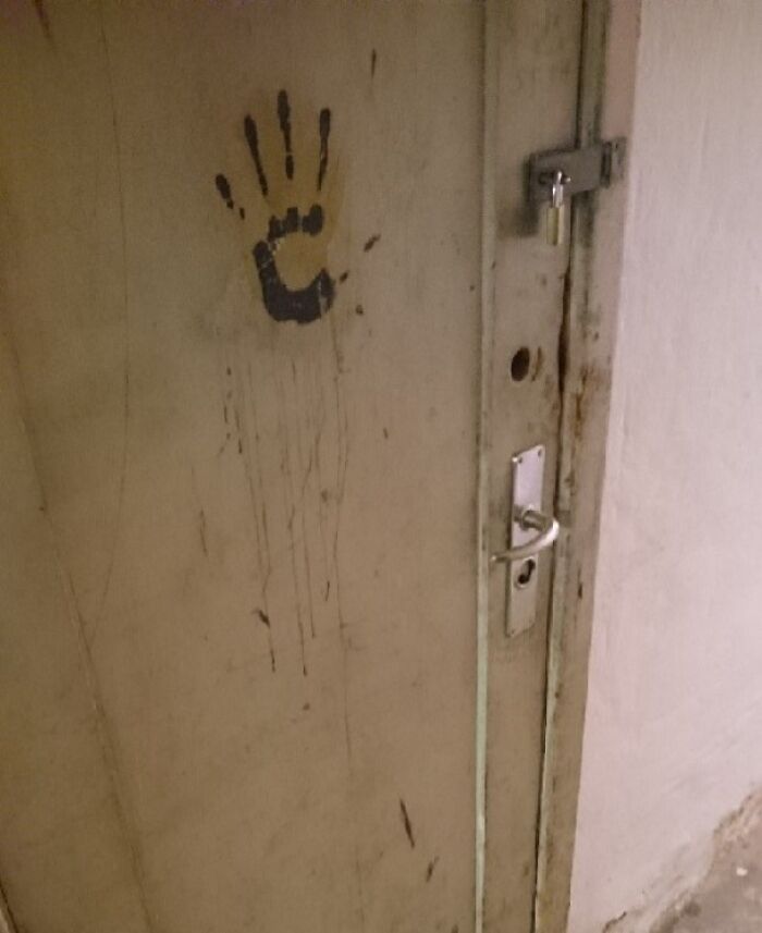 Huella de mano pintada en puerta vieja con cerrojo en casa nueva, causando miedo y sorpresa a los nuevos residentes.