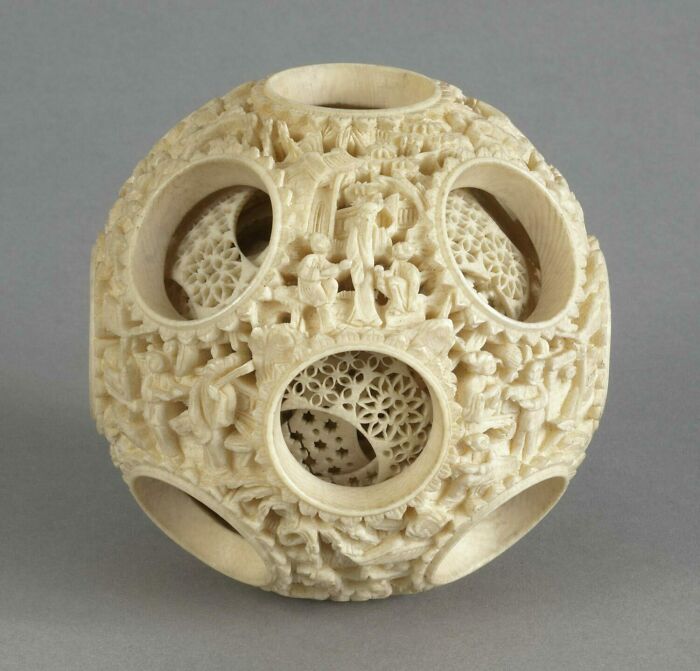 Intricately carved ivory artifact with multiple layers and detailed patterns, showcasing historical craftsmanship.