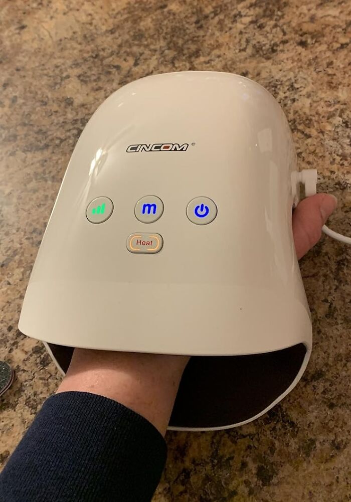 Hand using a CINCOM massager on a brown surface for a unique gift idea.