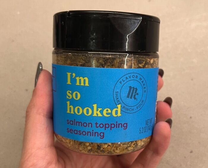 Hand holding a jar of salmon topping seasoning labeled "I'm so hooked," ideal for unique gift ideas.