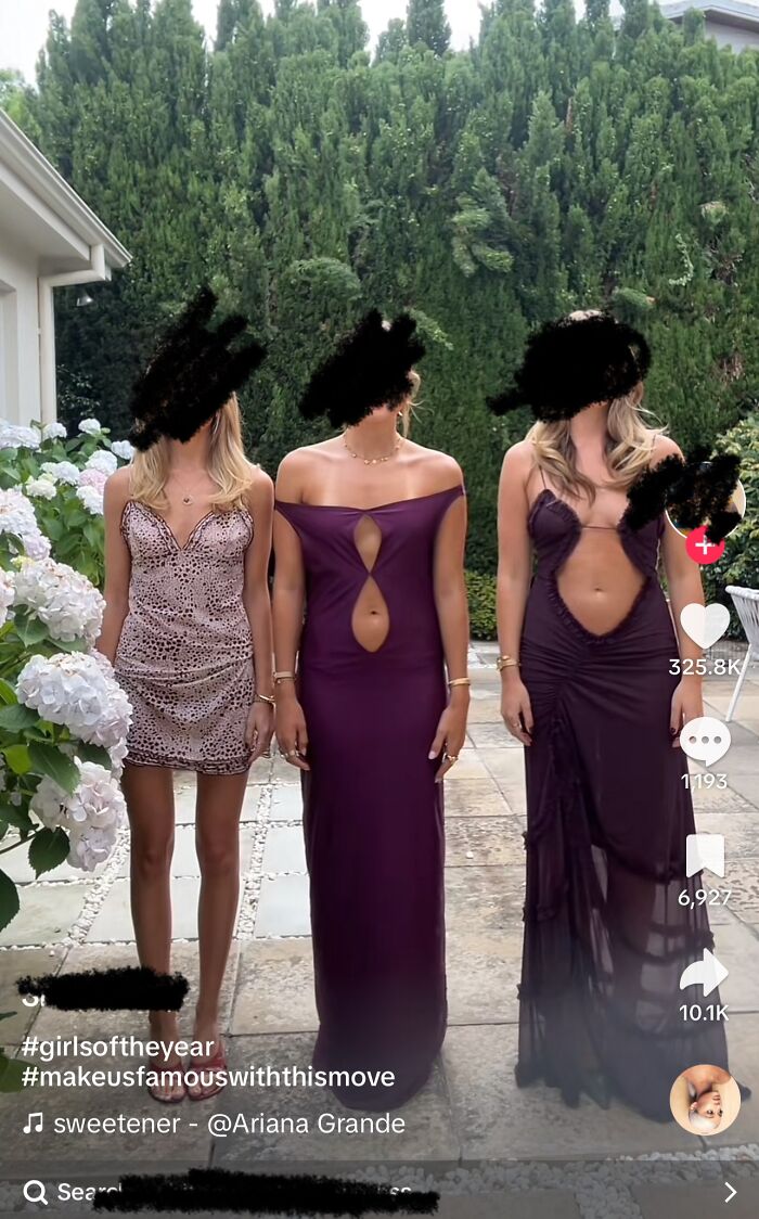 Three women in unconventional dresses, possibly considered a fashion crime, standing outdoors near flowering bushes.