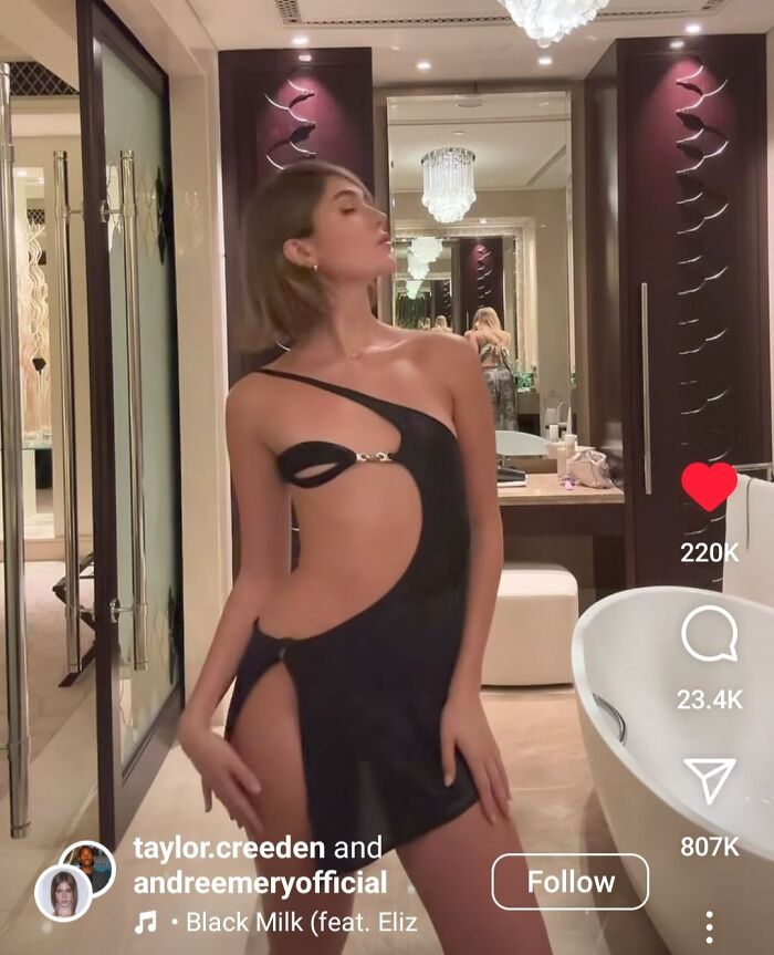 Person wearing a black cutout dress in a modern bathroom, showcasing a fashion crime with a unique design.