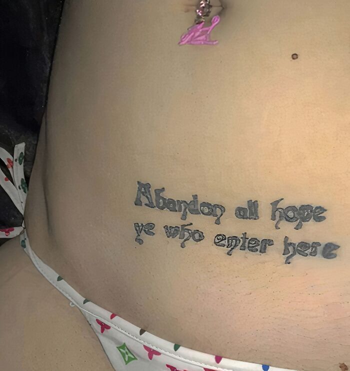 Tattoo mistake with text: "Abandon all hope ye who enter here" on skin, showcasing a permanent ink error.