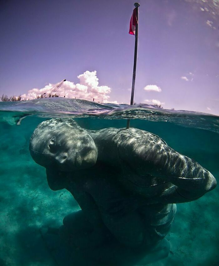Underwater statue of a human figure partially submerged, representing strange oceanic discoveries.