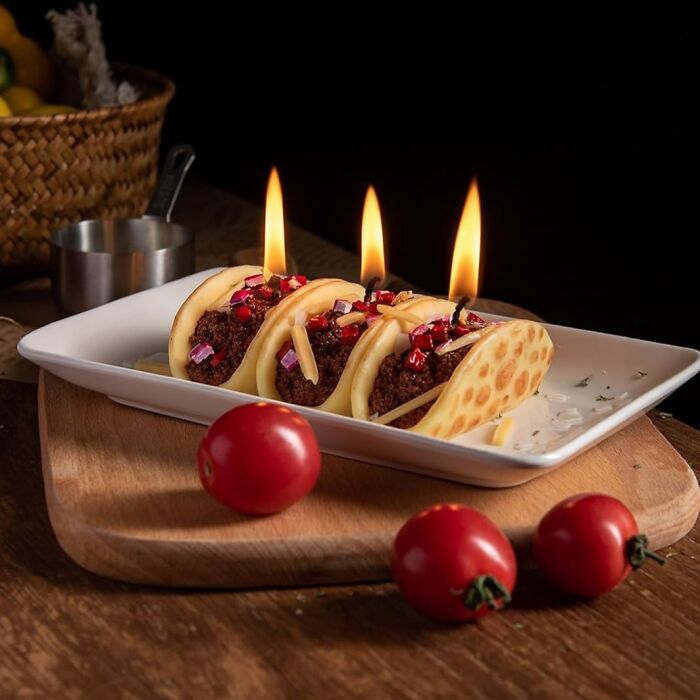 Candles shaped like tacos, a creative wax masterpiece on a white plate with cherry tomatoes.