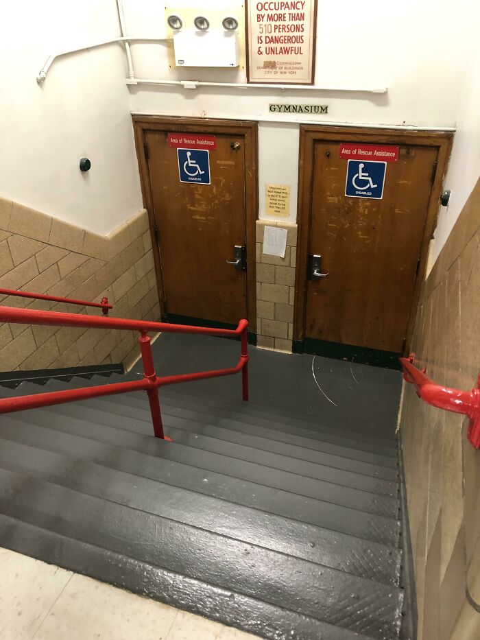 Stairs lead to gymnasium doors marked for disability access, highlighting a city planner oversight.