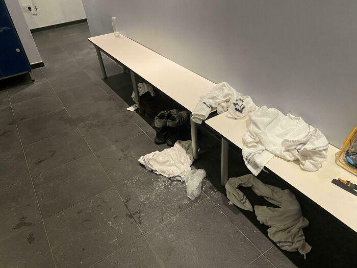 Messy gym locker room with shoes and towels strewn on the floor, highlighting lack of basic etiquette.