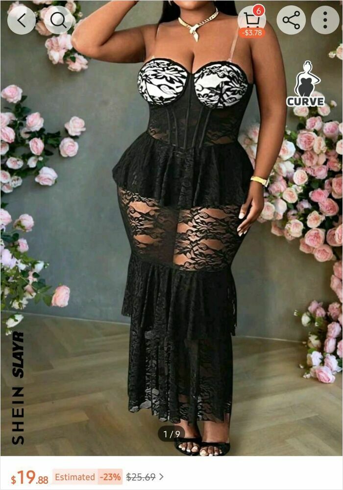 Woman in a black lace dress with floral accents, posing indoors, showcasing a bold fashion choice.