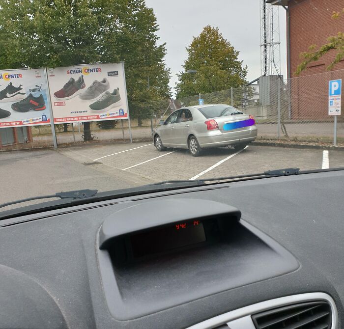 Car parked poorly across two parking spaces, highlighting lack of basic etiquette.