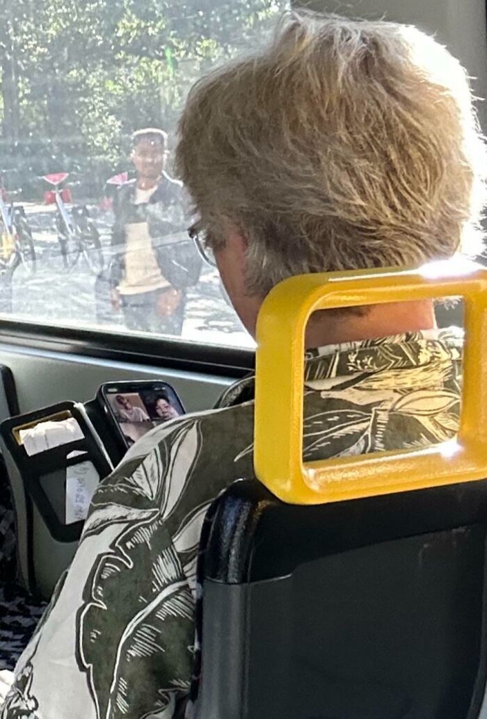 Person watching video on phone loudly in public, showing lack of basic etiquette.