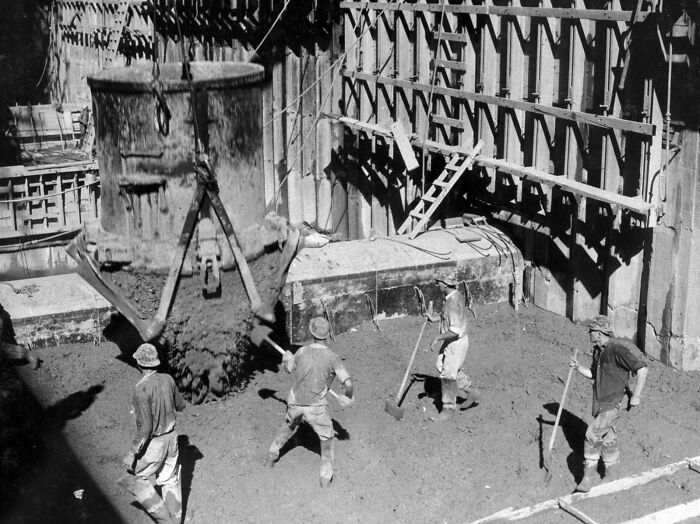 Workers mixing concrete during construction, showcasing historical coincidences in architecture.