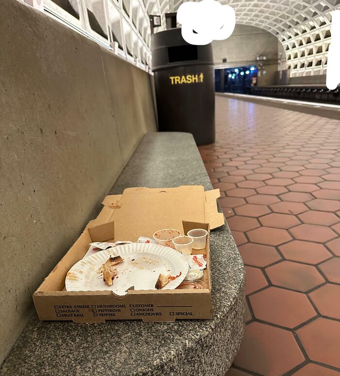 Empty pizza box and trash left on a subway station bench, illustrating a lack of basic etiquette.
