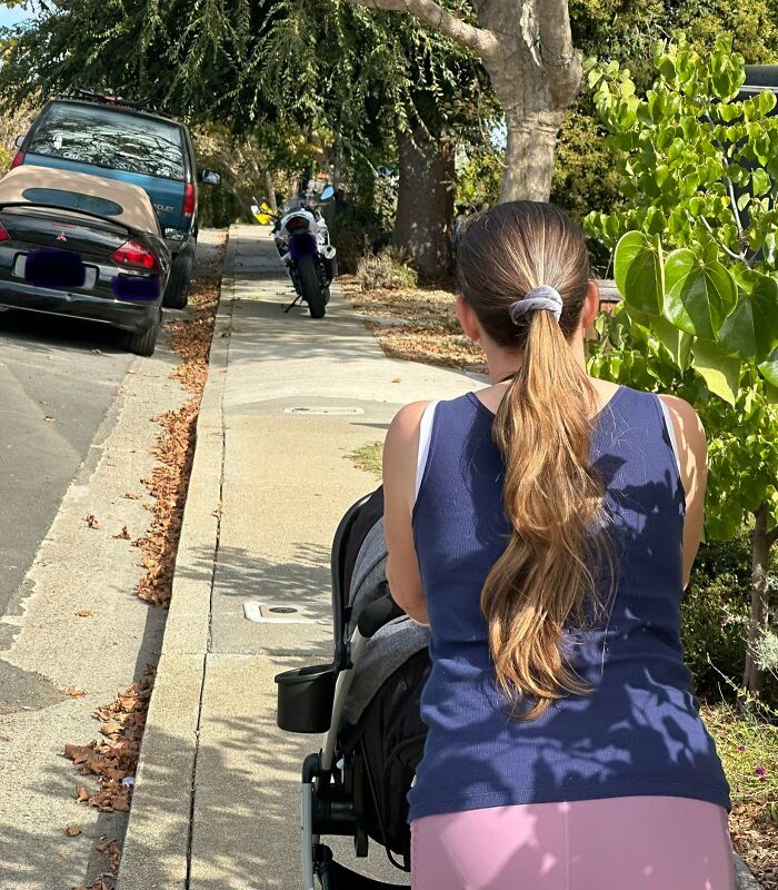 Woman with stroller faces blocked sidewalk by parked cars, illustrating lack of basic etiquette.