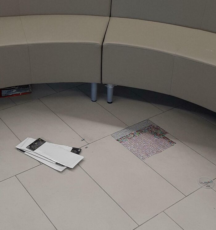 Litter on tiled floor near a curved bench, highlighting lack of basic etiquette.