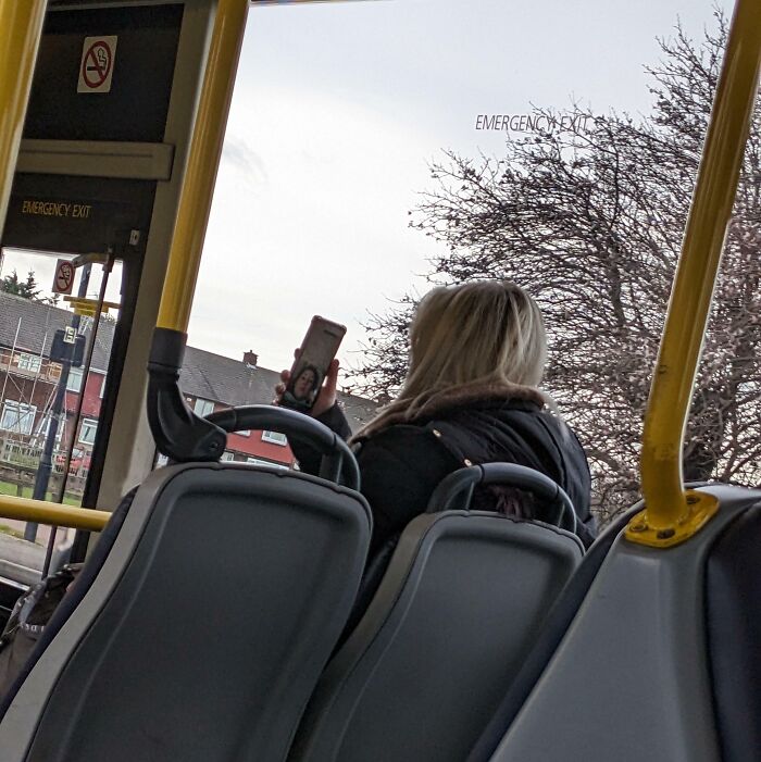 Person using phone on bus, ignoring basic etiquette.