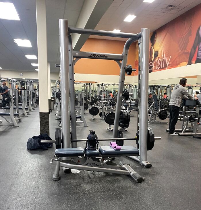 Gym weights left on equipment, lacking basic etiquette, with a towel on the bench.