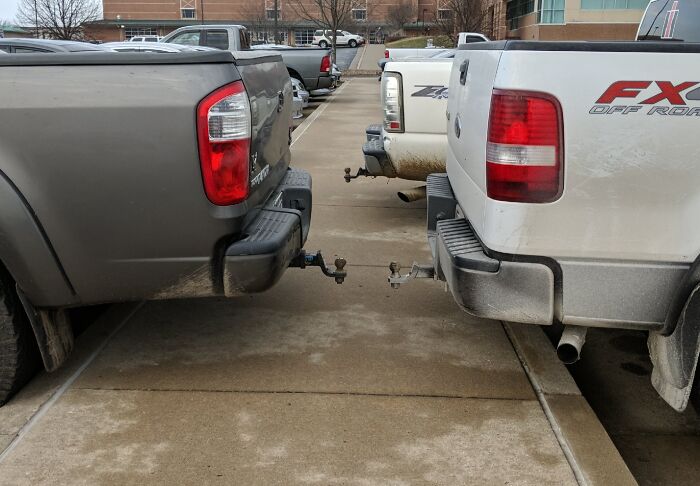 Two trucks parked improperly with rear bumpers touching, showcasing a lack of basic etiquette.