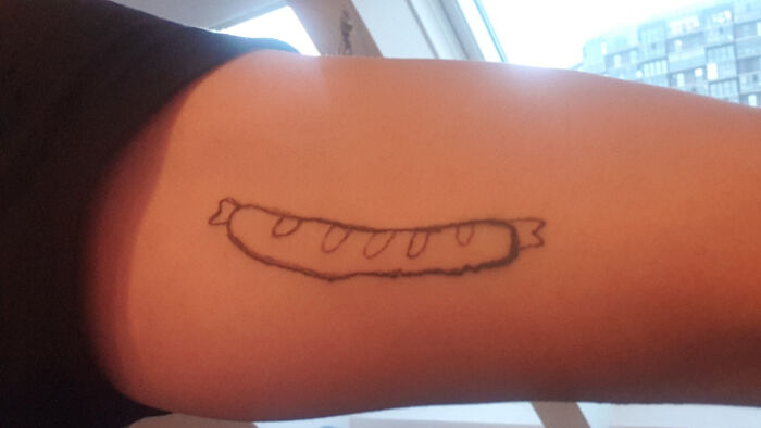 Close-up of a simple tattoo on an arm showing a poorly drawn sausage, an example of wild tattoo fails.