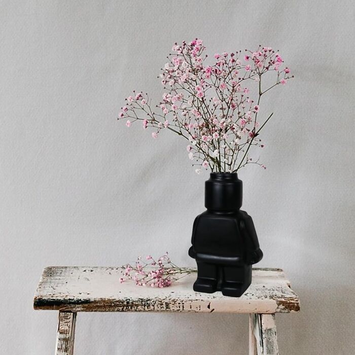 Unique black vase with flowers on a rustic stool, enhancing a generic apartment's charm.