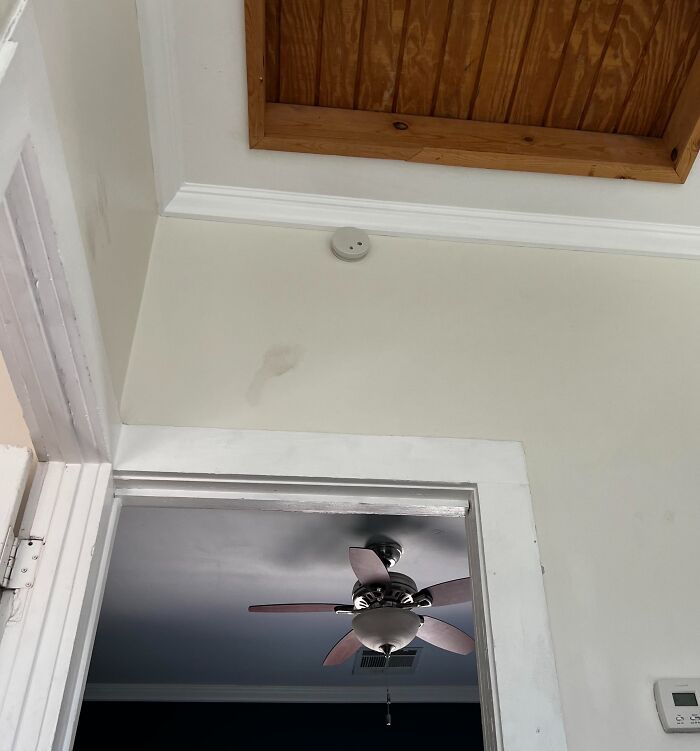 Ceiling with hidden wooden hatch above doorway in a home.
