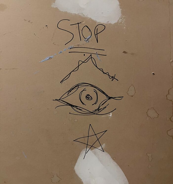 Creepy drawings on a wall including an eye, mountain, and star with the word "STOP" above.