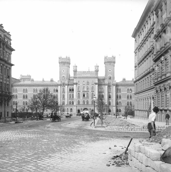Black and white photo showing life in Europe 100 years ago with historic buildings and cobblestone street.