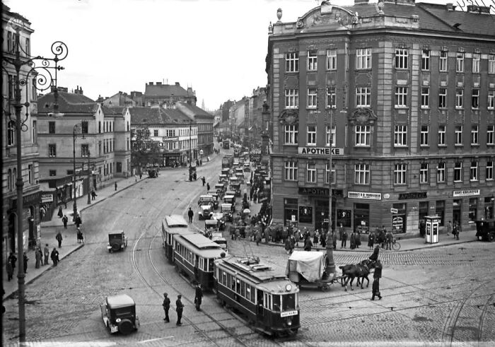 Busy street with trams, cars, and pedestrians in a European city showing life in Europe 100 years ago.