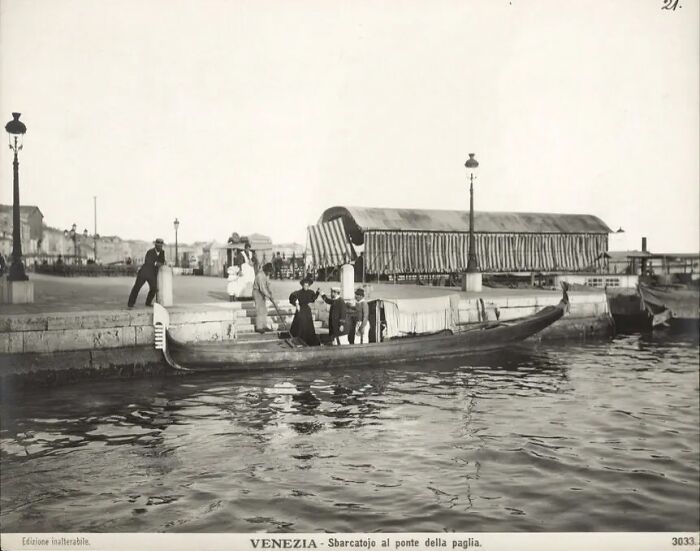 Vintage black and white photo showing life in Europe 100 years ago with people boarding a gondola in Venice.