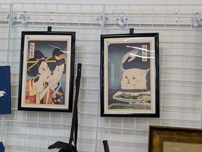 Framed bizarre artwork from Goodwill featuring surprised figures and a cat at a dinner table on a grid wall.