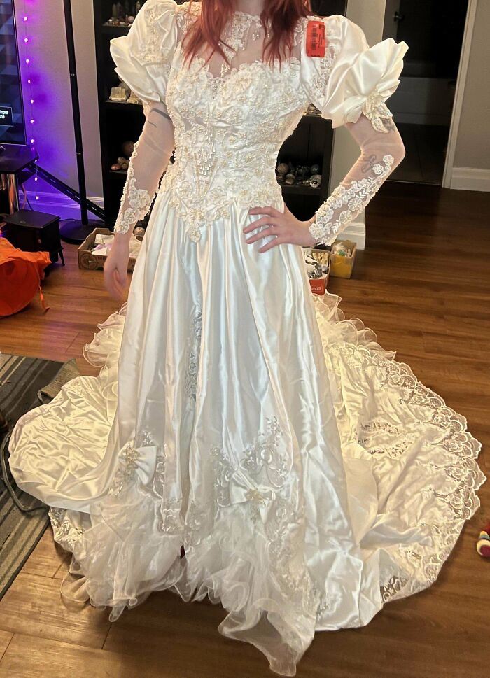 Person in an elaborate vintage white wedding dress found at Goodwill.