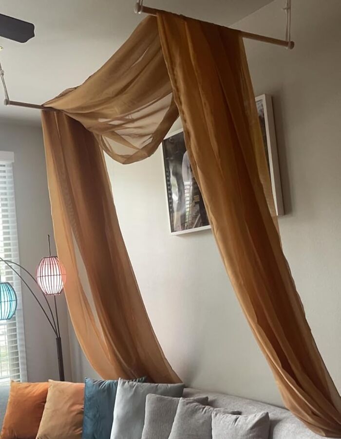 Sheer gold curtain draped artfully in a modern living room, showcasing trendsetting treasures with colorful cushions and lamps.