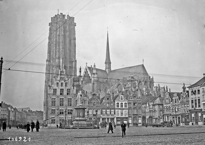 Historic city square in Europe with cathedral and people walking, illustrating life in Europe 100 years ago.