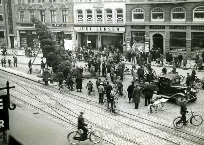 Crowd of people with bicycles gathered on a cobblestone street in Europe, showing life in Europe 100 years ago.