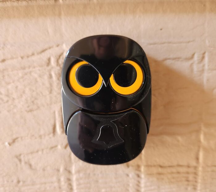 Black owl-shaped doorbell on a brick wall, showcasing trendsetting treasures.