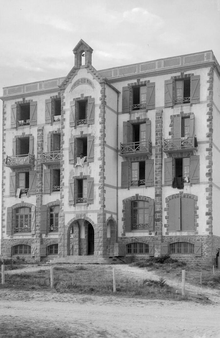 Old European residential building with open shutters and laundry hanging, depicting life in Europe 100 years ago.