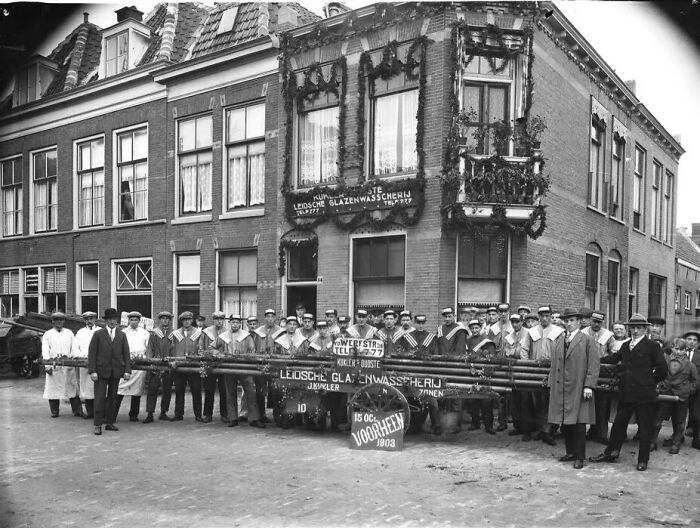 Group of European workers posing outside a decorated building, illustrating life in Europe 100 years ago.