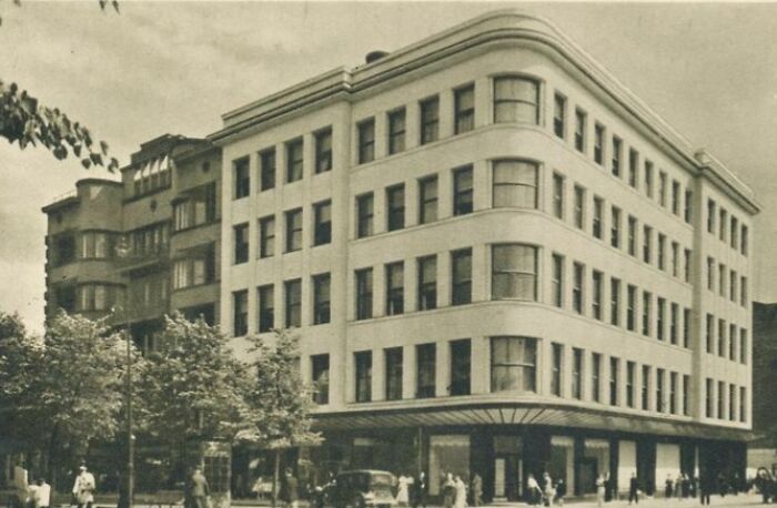 Vintage photo showing life in Europe 100 years ago with historic urban architecture and people on the street.