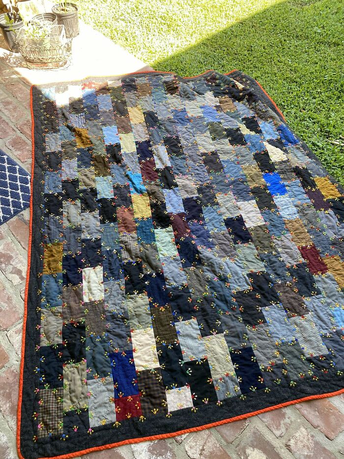 Patchwork quilt on a patio, an unexpected Goodwill gem with colorful rectangular patches and orange trim.