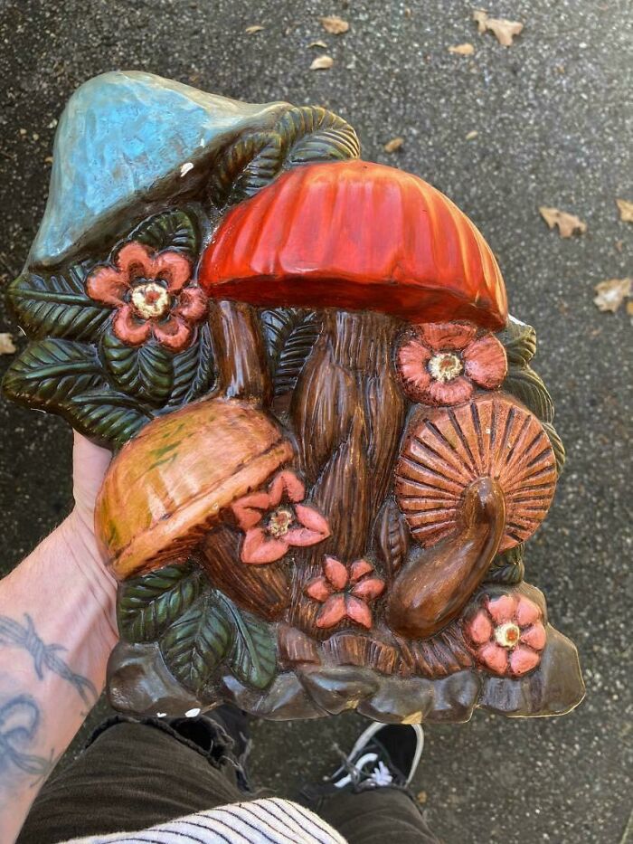 Colorful mushroom sculpture from Goodwill, featuring red, blue, and orange mushrooms surrounded by pink flowers and green leaves.