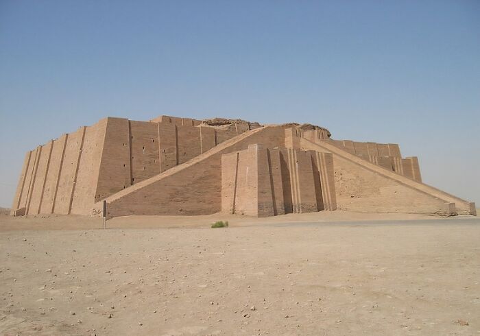 Ancient ziggurat under clear sky, an architectural wonder not very well-known, made of brown bricks with steps.