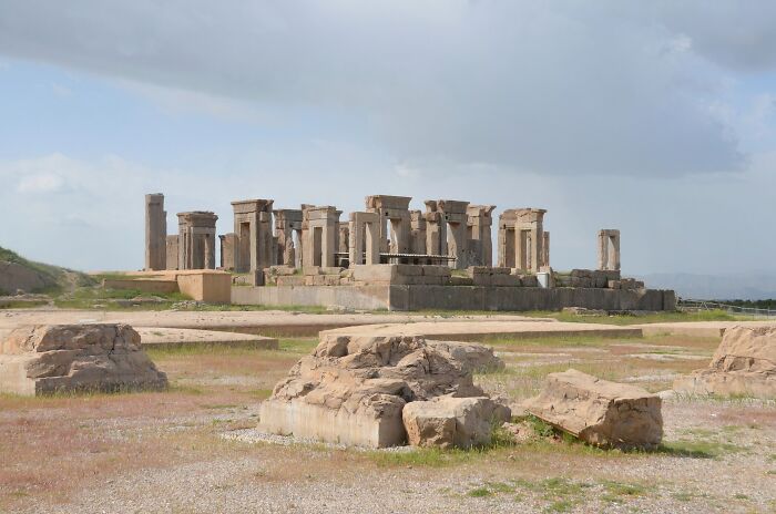 Ancient architectural wonder with stone columns and ruins under a cloudy sky, showcasing historical grandeur.