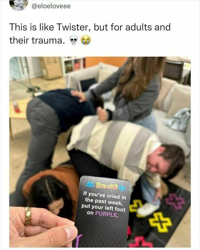 Adults play a humorous game resembling Twister, with a card prompting emotional actions, adding a funny twist.