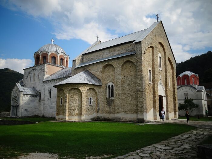 A historic architectural wonder with stone walls and domed roofs, surrounded by green grass under a cloudy sky.