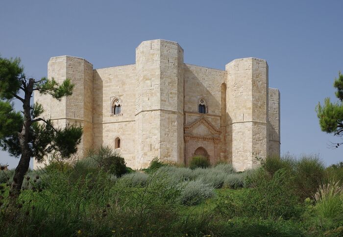 Majestic architectural wonder with octagonal towers, surrounded by greenery under a clear sky.