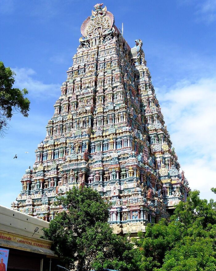Colorful temple tower, an architectural wonder surrounded by trees under a blue sky.