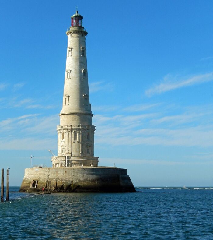 A lighthouse by the sea, showcasing an architectural wonder against a clear blue sky.